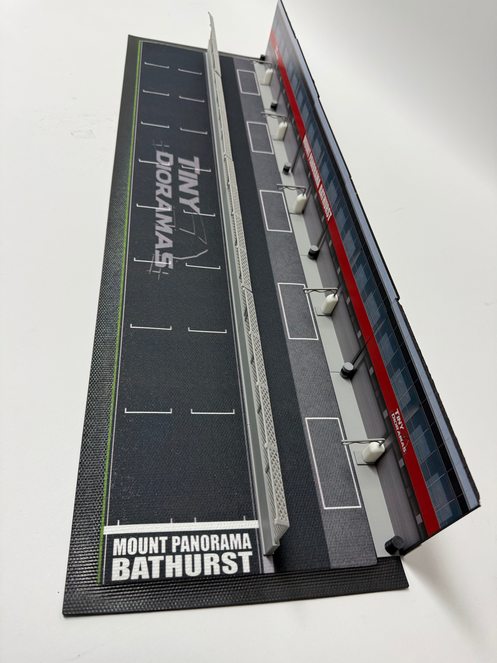 Model of a race track with 'Tiny Doramas' branding on a white background